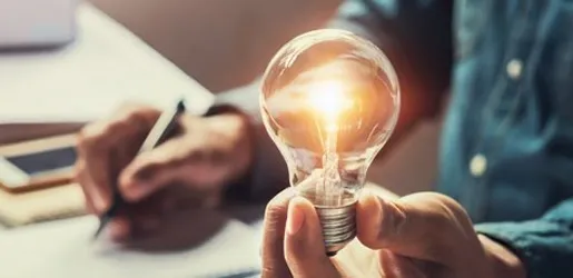 Ampoule allumée tenue au-dessus d'un plan d'installation électrique.