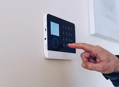 Main activant un boîtier domotique ou alarme électrique mural.